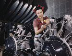 Free Picture of Woman standing between sections of motor, working with wires