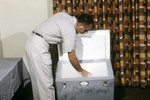 Free Picture of Field Researcher Placing Pint Cartons Containing Mosquito-Filled Tubes Into a Freezer to Preserve the Specimens