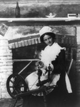 Free Picture of Woman Using a Spinning Wheel by a Fireplace